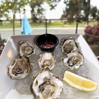 Leila by the Bay - Oyster Saturdays - FI - Oysters on a plate with partial view of the restaurant.